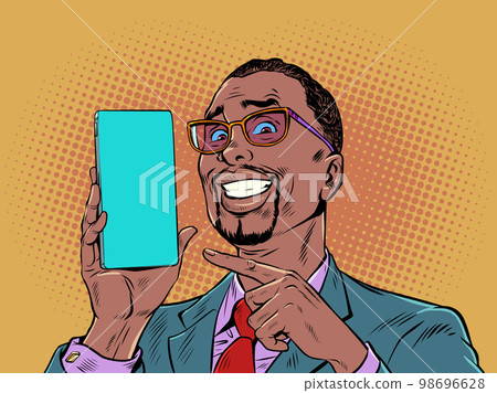A man with black hair and fashionable glasses smiles and points to the phone. Product demonstration or offer on smartphone. The joy of a perfect purchase. Pop Art Retro A man with black hair and fashionable glasses smiles and points to the phone. Product demonstration or offer on smartphone. The joy of a perfect purchase. Pop Art Retro 98696628