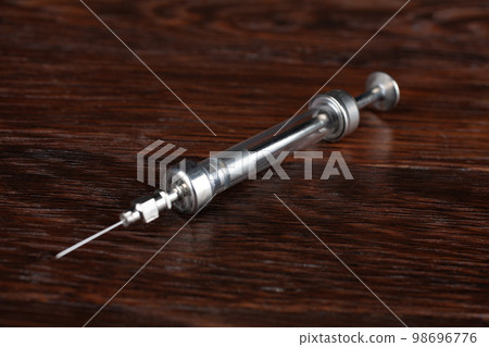 Antique syringe on a wooden table. 98696776