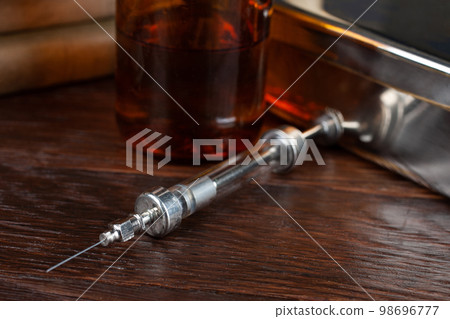 Antique syringe on a wooden table. 98696777