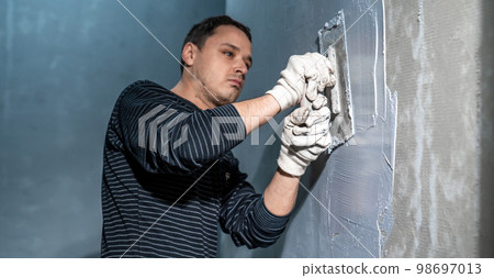 man applies insulation to a bathroom wall 98697013
