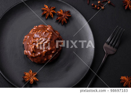 Delicious chocolate tart with nuts on a black ceramic plate Delicious chocolate tart with nuts on a black ceramic plate 98697183