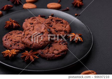 Delicious chocolate cookies with nuts on a black ceramic plate Delicious chocolate cookies with nuts on a black ceramic plate 98697210