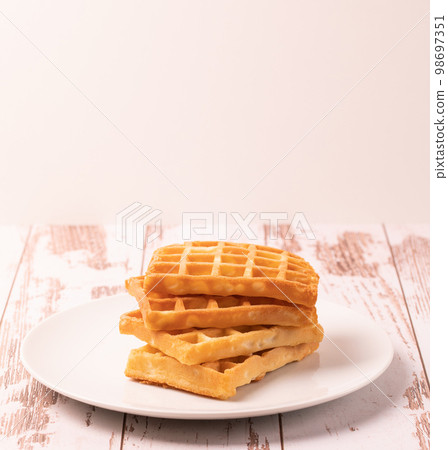 Delicious Belgian waffles served on white plate and wooden background, rustic concept. Delicious Belgian waffles served on white plate and wooden background, rustic concept. 98697351