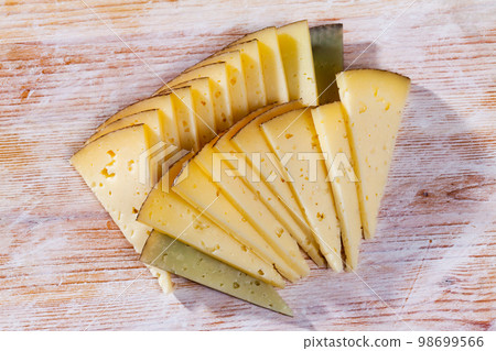 Appetizing slice of semi-hard cheese 98699566
