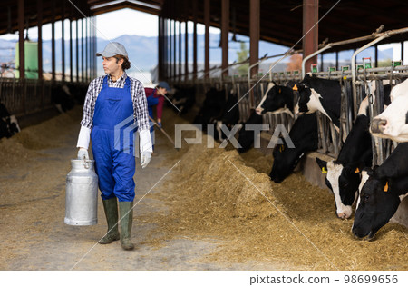Farmer man holds milk can at cow farm Farmer man holds milk can at cow farm 98699656