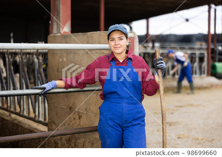Farmer woman stands with rake at cow farm Farmer woman stands with rake at cow farm 98699660