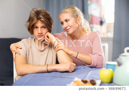 Mother and son sitting after quarrel at home Mother and son sitting after quarrel at home 98699671