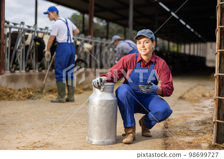 Young woman farmer with can works on dairy farm Young woman farmer with can works on dairy farm 98699727