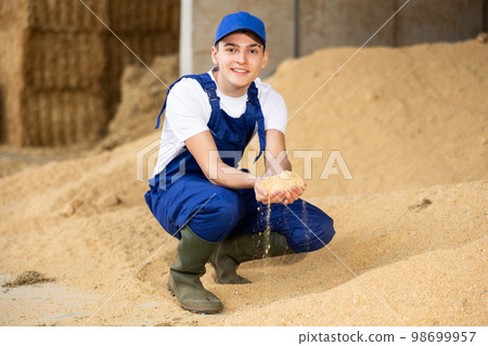 Positive male farmer with handful of soybean husk feed in hands Positive male farmer with handful of soybean husk feed in hands 98699957