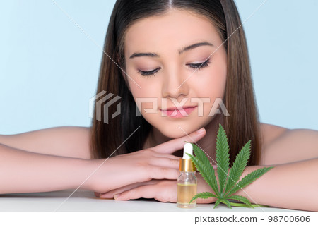 Young charming girl applying CBD serum from cannabis extracted oil for skincare. Young charming girl applying CBD serum from cannabis extracted oil for skincare. 98700606