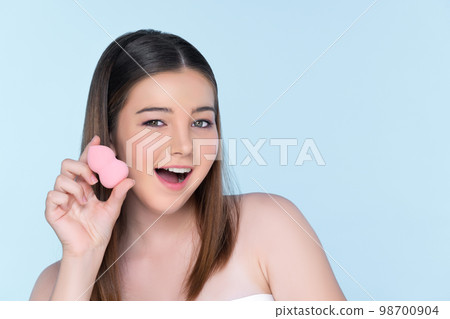Portrait of young charming girl applying dry powder foundation on her face. Portrait of young charming girl applying dry powder foundation on her face. 98700904