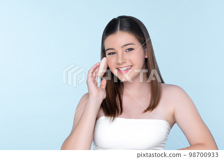 Portrait of young charming girl applying dry powder foundation on her face. 98700933