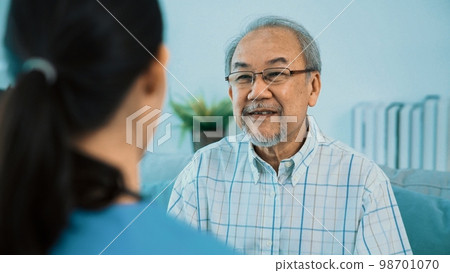 Young female doctor inquires personal data of a contented senior at home. 98701070