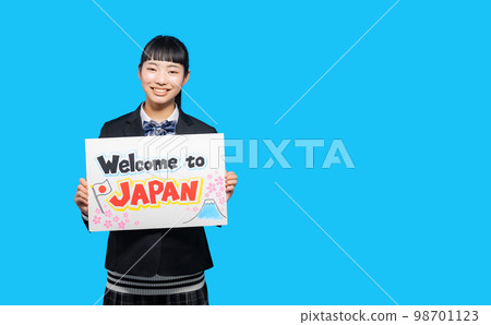 A female student holding a board welcoming tourists Welcome to Japan A female student holding a board welcoming tourists Welcome to Japan 98701123