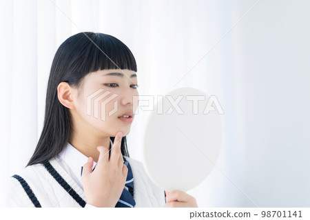 A female student who is worried about rough skin looking at the mirror 98701141