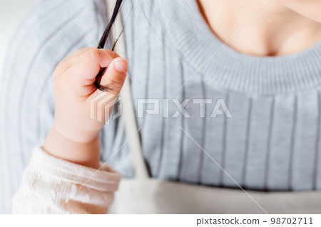 Child's hand pulling mom's hair 98702711