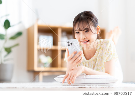 在客廳裡操作智能手機的年輕女子。 98703517