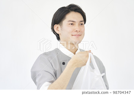 A male clerk at a cake shop handing over the product White background A male clerk at a cake shop handing over the product White background 98704347