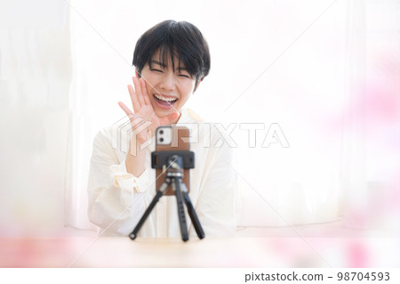 A cute woman streaming videos on her smartphone Spring-like image 98704593