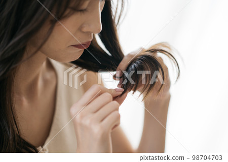 Women who suffer from damaged hair, split ends, and curly hair Women who suffer from damaged hair, split ends, and curly hair 98704703