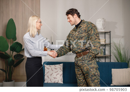 Soldier and psychiatrist standing in room after therapy session. Man wearing military uniform. Male warrior with ptds shaking hand of psychiatrist. 98705903
