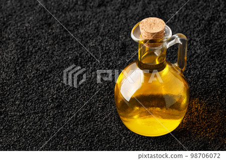 black cumin oil in bottle and scattered seeds as background black cumin oil in bottle and scattered seeds as background 98706072