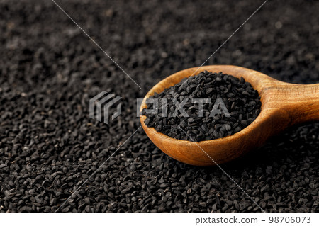 black cumin seeds in scoop and scattered on background black cumin seeds in scoop and scattered on background 98706073