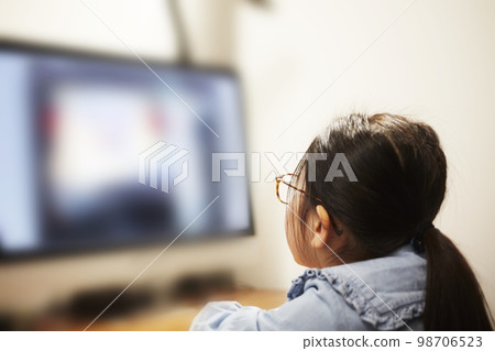 Child girl watching video distribution on computer monitor Child girl watching video distribution on computer monitor 98706523