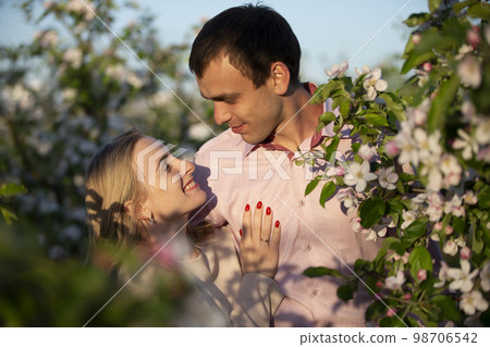 Young happy couple in love outdoors. loving man and woman on a walk in a spring blooming park 98706542