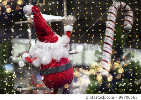 On a Christmas background, a toy santa claus climbs a rope ladder against a background of golden bokeh. 98706563