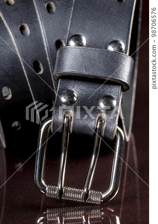 Black leather belt on a dark background. Leather products. 98706576