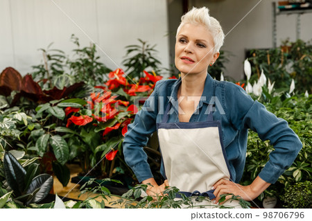 Thoughtful gardener female resting after work enjoying her greenhouse. 98706796