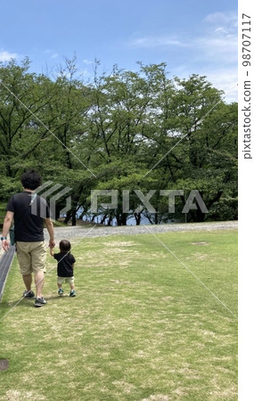 父母和孩子牽著手走在陽光明媚的公園裡 父母和孩子牽著手走在陽光明媚的公園裡 98707117