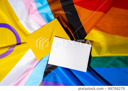 Empty paper blank on Rainbow LGBTQIA flag made from silk material. Mock up template copy space for your text. Symbol of LGBTQ pride month. Equal rights. Peace and freedom. Support LGBTQIA community 98708270