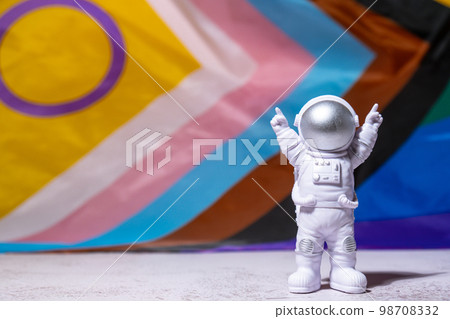 Toy astronaut on Rainbow LGBTQIA flag made from silk material background. Happy pride month. Symbol of LGBTQ pride month. Equal rights. Peace and freedom. Support LGBTQIA community Toy astronaut on Rainbow LGBTQIA flag made from silk material background. Happy pride month. Symbol of LGBTQ pride month. Equal rights. Peace and freedom. Support LGBTQIA community 98708332