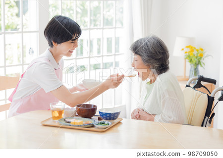 Nursing care image A caregiver assisting with meals 98709050
