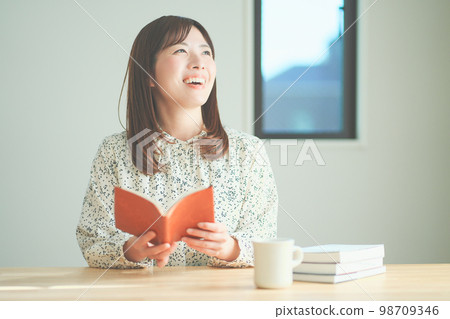 女人一邊讀書一邊享受下午茶時間 女人一邊讀書一邊享受下午茶時間 98709346