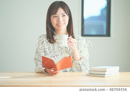 Woman enjoying tea time while reading 98709356