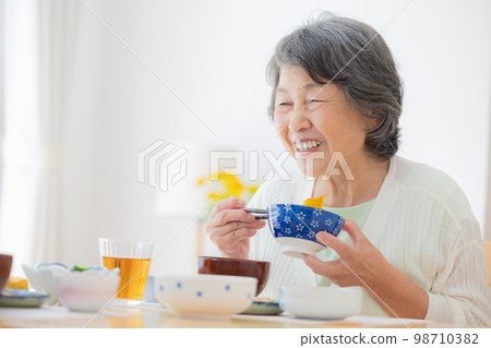 Meal scene A senior woman enjoying a meal 98710382