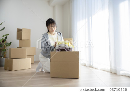 年輕女子把衣服放在紙板箱裡移動圖像 年輕女子把衣服放在紙板箱裡移動圖像 98710526