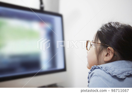 Child girl watching video distribution on computer monitor Child girl watching video distribution on computer monitor 98711087
