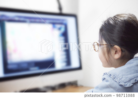 Child girl watching video distribution on computer monitor Child girl watching video distribution on computer monitor 98711088