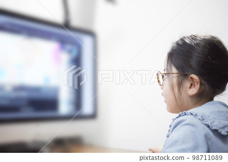 在電腦顯示器上觀看視頻分發的女童 在電腦顯示器上觀看視頻分發的女童 98711089