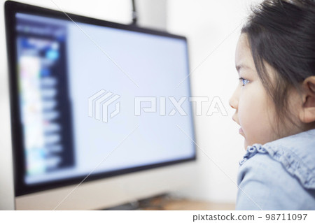 Child girl watching video distribution on computer monitor Child girl watching video distribution on computer monitor 98711097