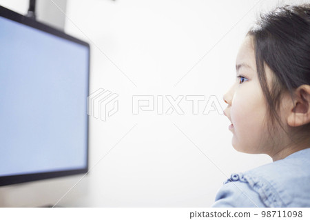 Child girl watching video distribution on computer monitor Child girl watching video distribution on computer monitor 98711098