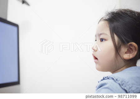 Child girl watching video distribution on computer monitor Child girl watching video distribution on computer monitor 98711099