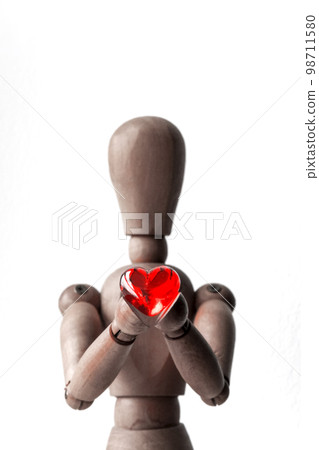 A red heart-shaped bead held by a wooden drawing doll with both hands A red heart-shaped bead held by a wooden drawing doll with both hands 98711580