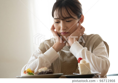 A woman on a diet who wants to eat cake but endures 98711908