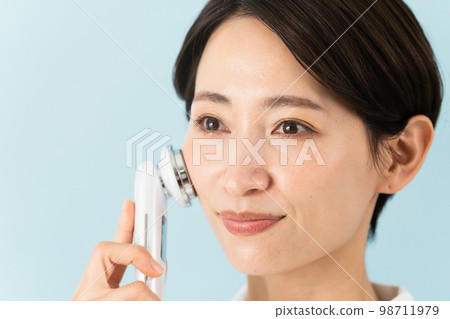 A young woman wearing a nurse uniform and explaining a facial massager Beauty image 98711979