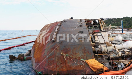 Close up of overturned rusty oil tanker ship in the shallow water. Drowned ship after the wreck. Close up of overturned rusty oil tanker ship in the shallow water. Drowned ship after the wreck. 98712291